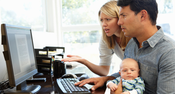 Couple working in home office with baby looking confused at the screen